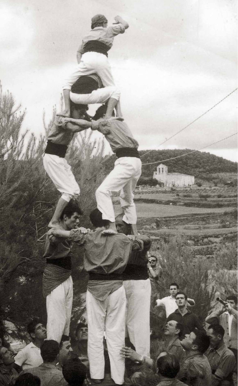 Pontons, 20-VIII-1961, al pati de cal Cinzano: el Ton Mata para a baixos, el Miró i l’Hill petit van al terç, el Mènec, l’Hill pare, el Lluís Giménez, el Xurro i d’altres (entre ells el Jordi Huguet, de paisà) s’ho miren, mentre el Ton Rubires toca la gralla, amb el pare Miret, tocant el timbal, al seu costat; al fons, l’església parroquial de Santa Magdalena